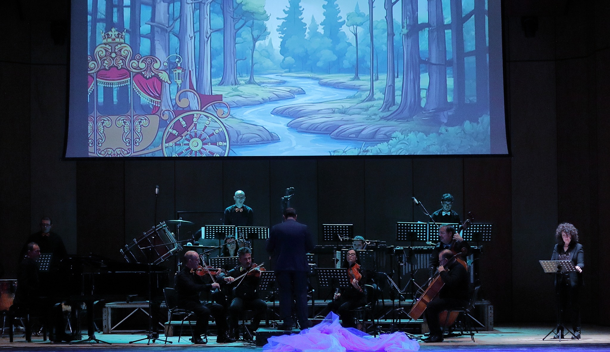 L'orchestra durante l'esibizione — animazione della carrozza reale e del bosco sullo schermo