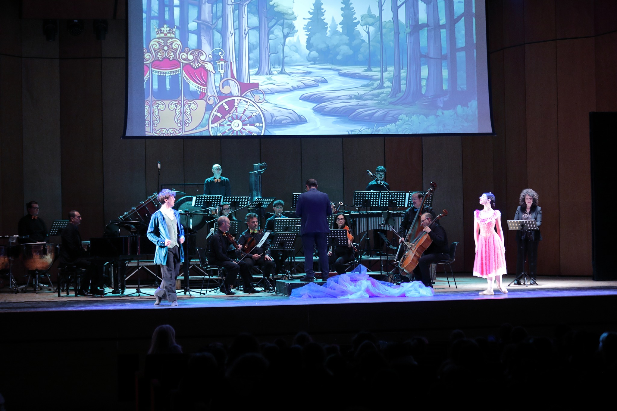 Il principe e la principessa in scena — danzatori con la carrozza nel bosco animata sullo schermo