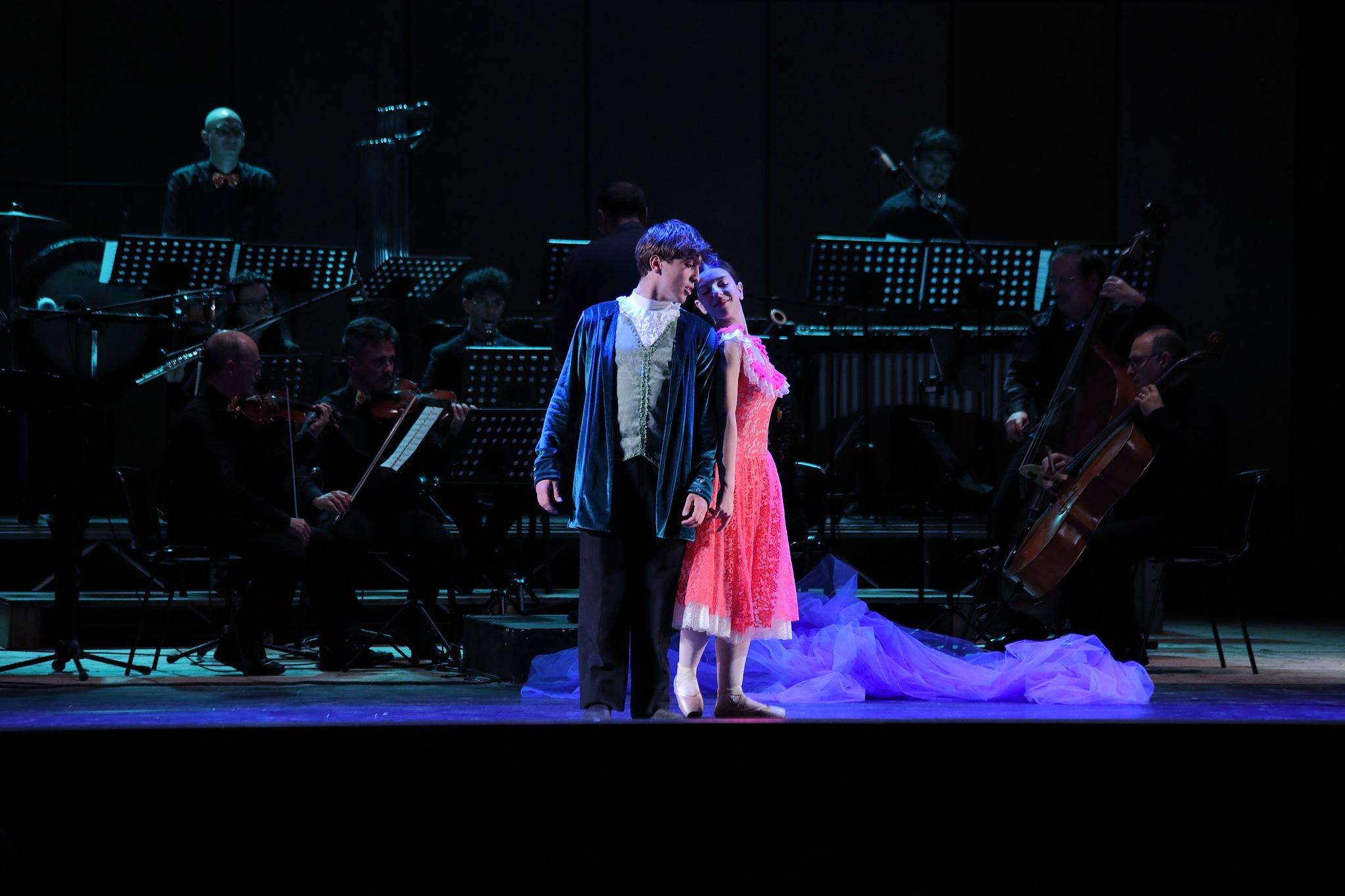Scena romantica — coppia di danzatori, abbraccio con l'orchestra, luce blu 2024