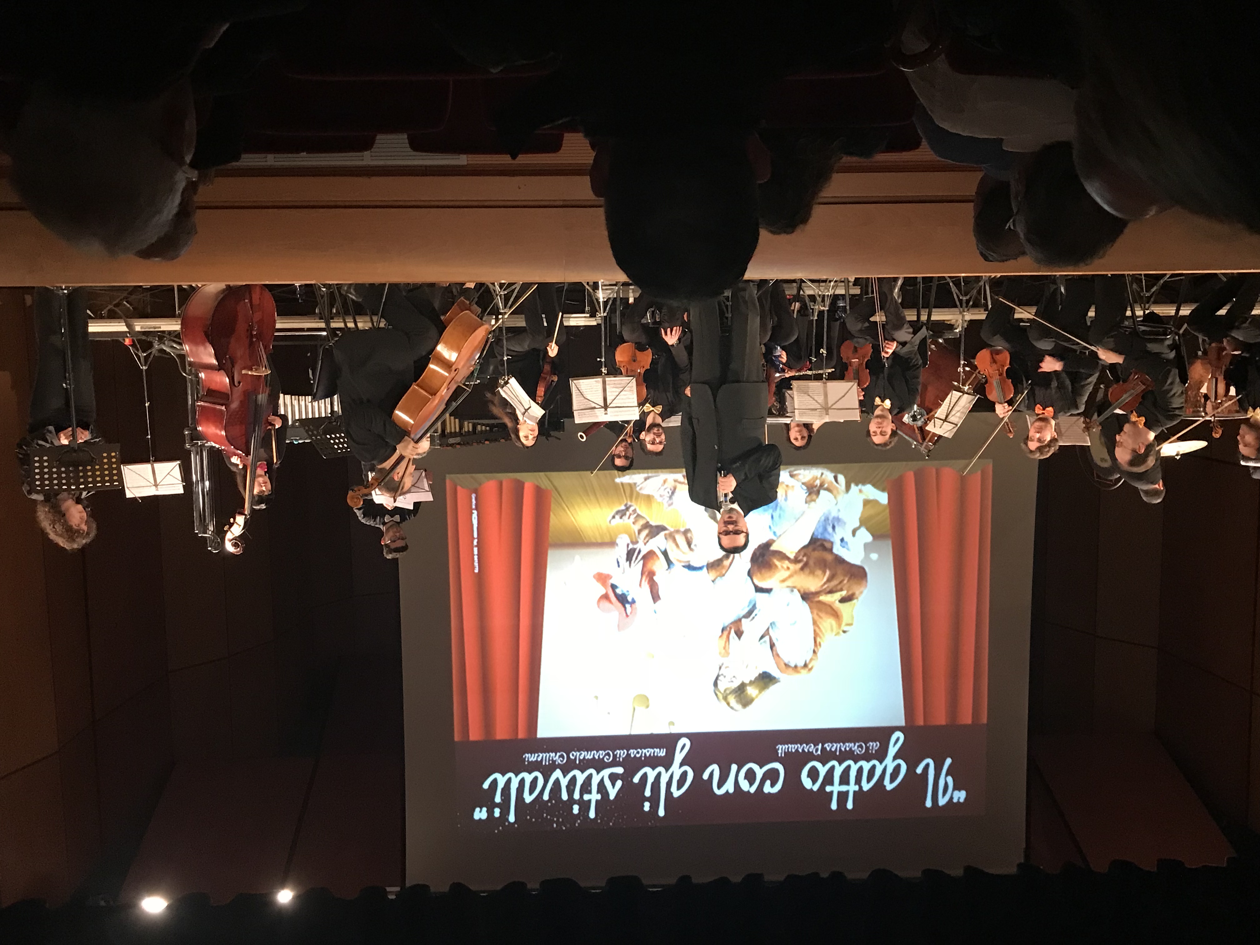 Il M° Carmelo Chillemi narratore sul palco — schermo con illustrazione del Gatto con gli Stivali